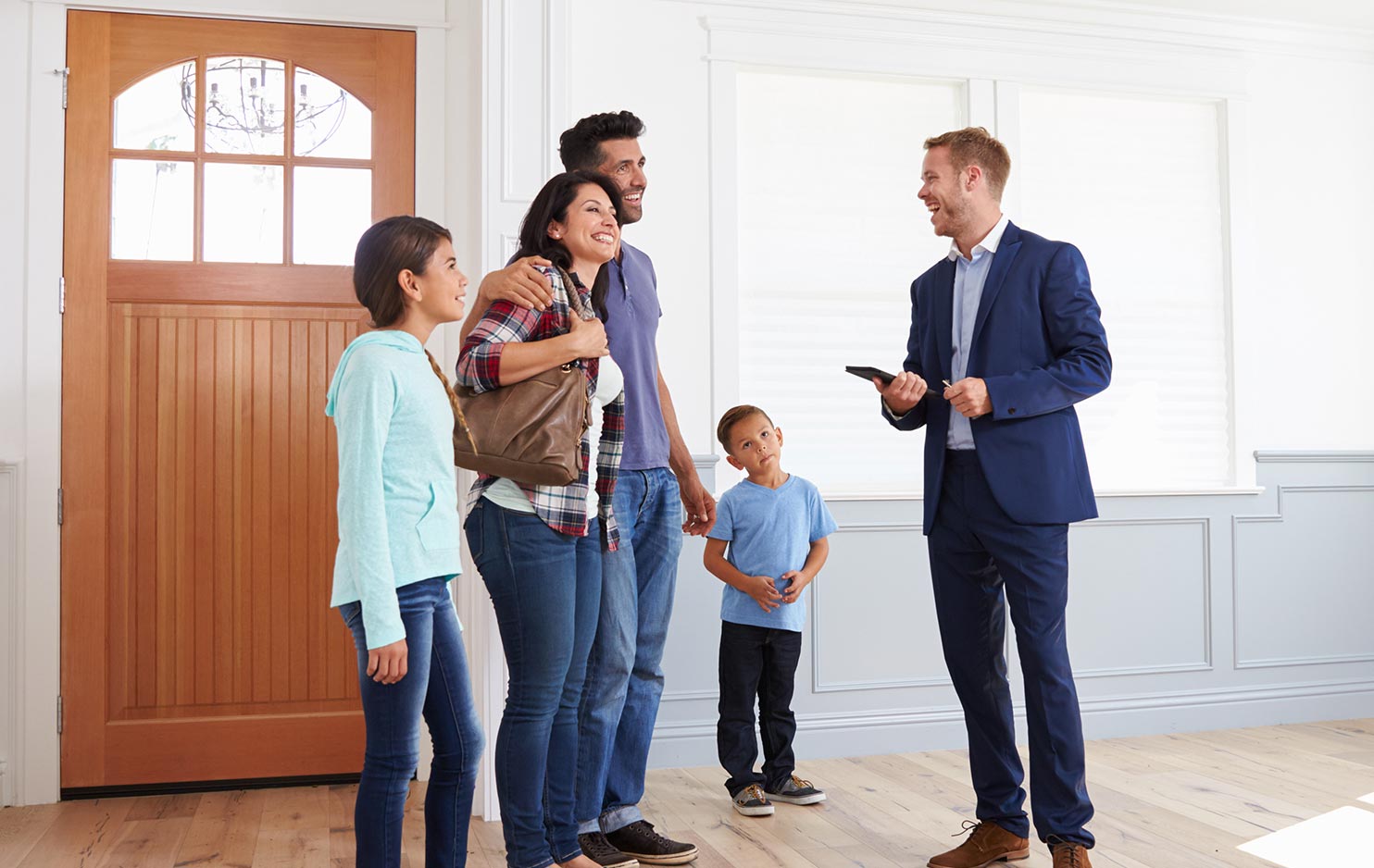 A family are smiling at an estate agent at a house viewing.