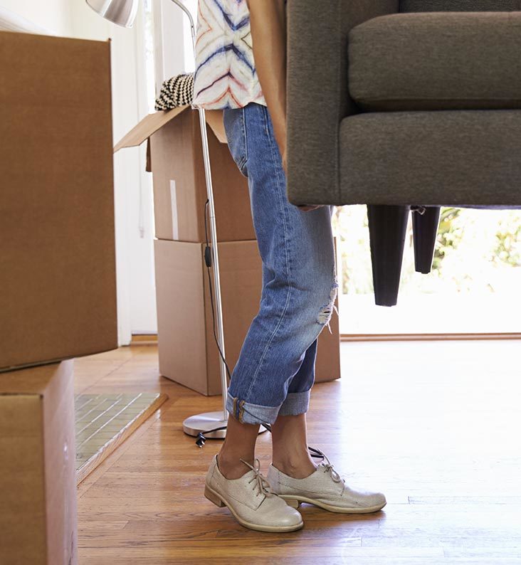 A close up of a woman's legs as she helps to carry a sofa.