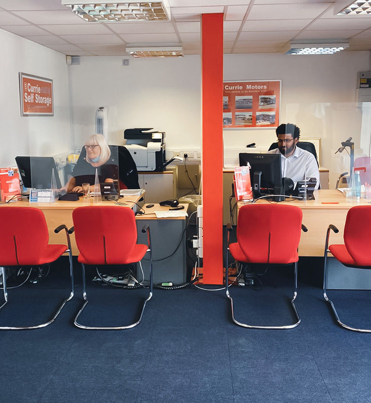 Two members of the Currie Storage customer service team are sat at their desks in our office.