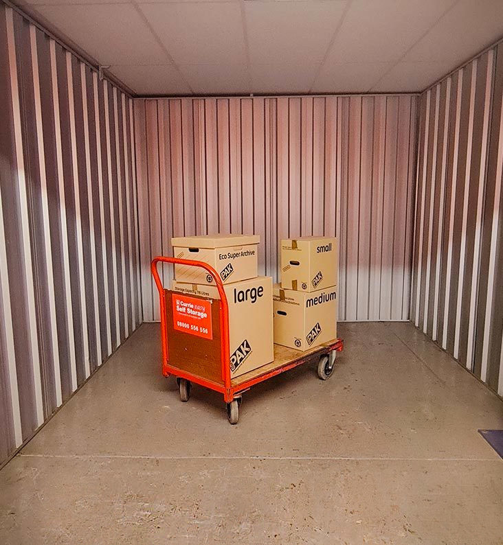 A pallet trolley is carrying 4 boxes into an empty storage unit.