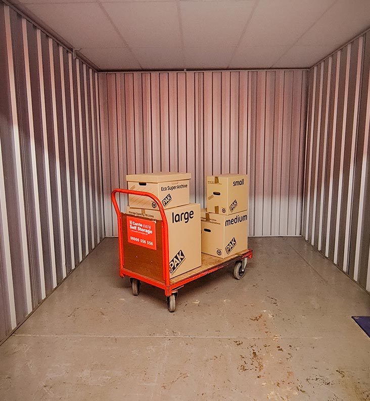 A pallet trolley is loaded with 4 boxes inside an empty storage unit.