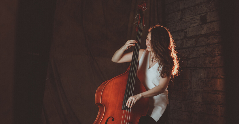 Woman in image playing double bass musical instrument.