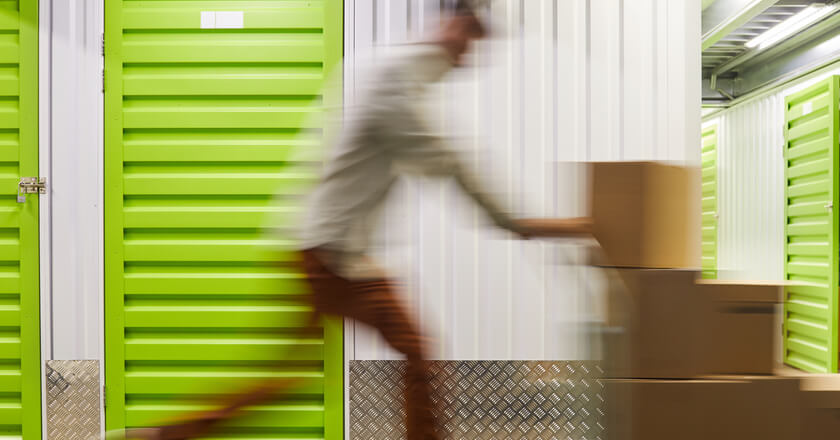Image of a man pushing boxes down the aisle of a self storage unit.