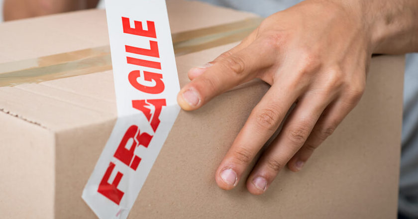 A hand sealing a box and getting their possessions ready for self storage.