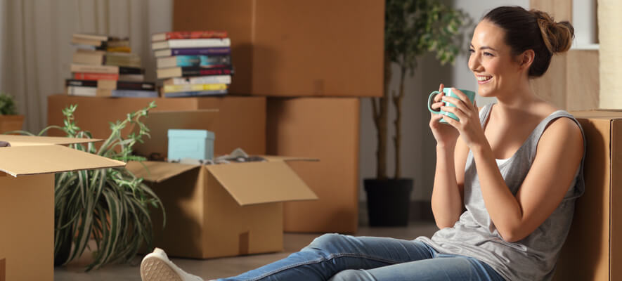 Image of woman sitting down with boxes after moving home.

