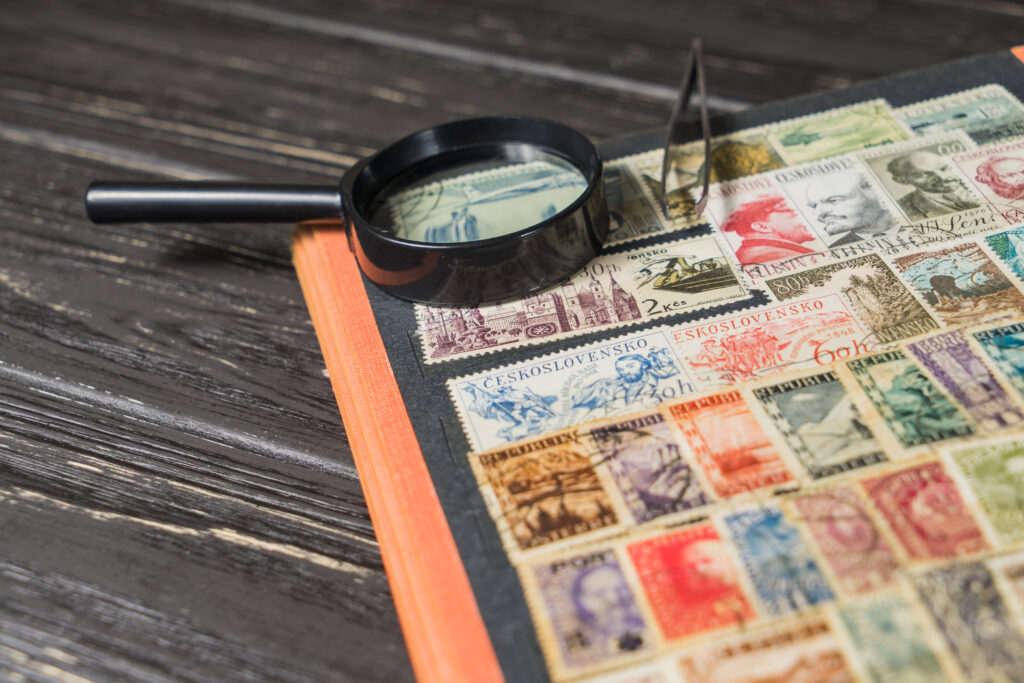 An image of a book of collected stamps and a magnifying glass.